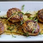 pan-seared scallops on plate topped with herbs and coffee vinaigrette