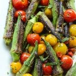 skillet blistered okra and tomatoes on a white platter