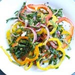 bell pepper salad with collard green strips and red onions on a plate.