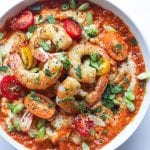 shrimp and grits in a bowl topped with red pepper sauce and cherry tomatoes